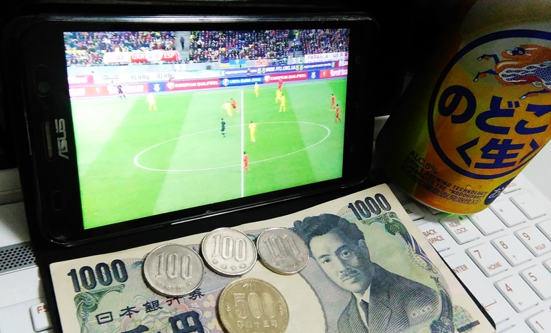 WOWOWオンデマンドでスマホでサッカーを見ながらビールと小銭1,800円が一緒に移った画像